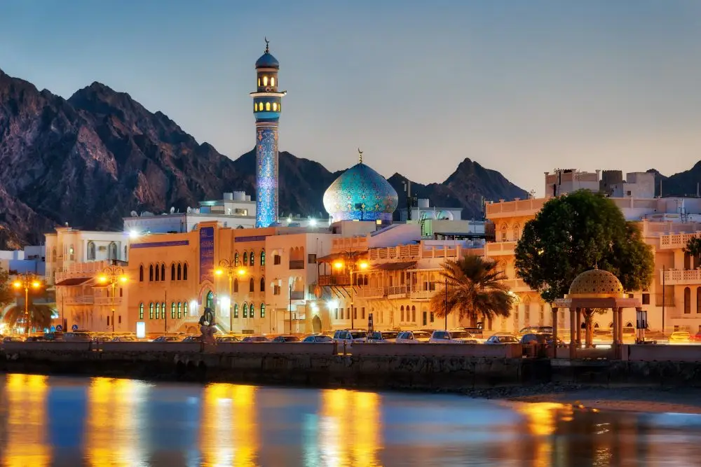 Muscat di sera, con la moschea illuminata e le montagne dell'Oman